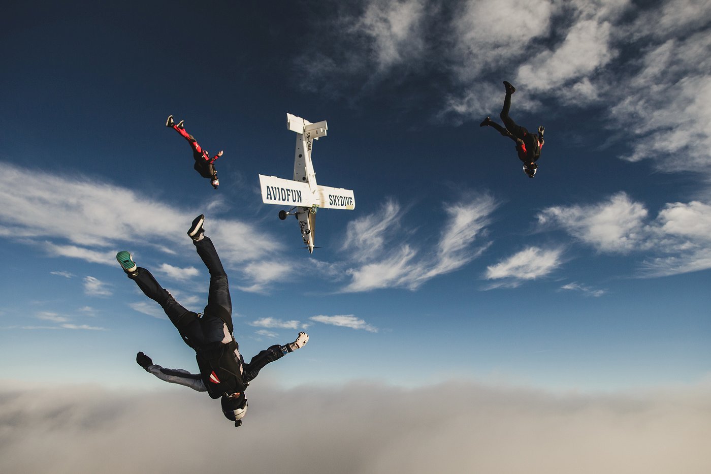 Skydivers descend along with the plane.